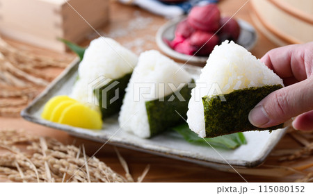 炊き立てのごはんに海苔を巻いたおむすびと、枡に盛ったお米と梅干し 炊き立てのごはんに海苔を巻いたおむすびと、枡に盛ったお米と梅干し 115080152