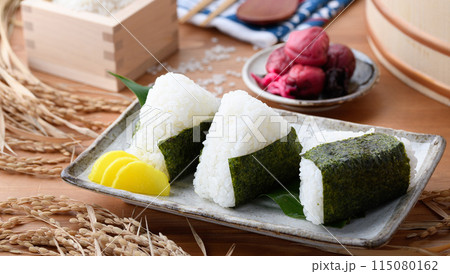 炊き立てのごはんに海苔を巻いたおむすびと、枡に盛ったお米と梅干し 炊き立てのごはんに海苔を巻いたおむすびと、枡に盛ったお米と梅干し 115080162