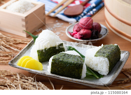 炊き立てのごはんに海苔を巻いたおむすびと、枡に盛ったお米と梅干し 115080164