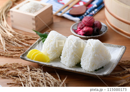 炊き立てのごはんに海苔を巻いたおむすびと、枡に盛ったお米と梅干し 炊き立てのごはんに海苔を巻いたおむすびと、枡に盛ったお米と梅干し 115080173
