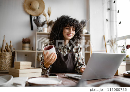 Owner of pottery workshop updates database of items that sold on website. 115080786