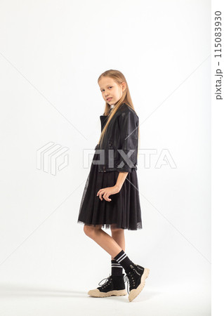 A full-length portrait of a young girl with long brown hair dressed in a hooligan style. A full-length portrait of a young girl with long brown hair dressed in a hooligan style. 115083930