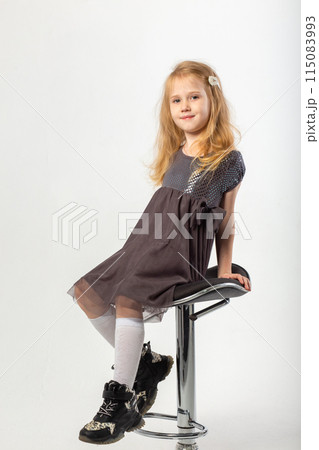 A little blonde girl in a leather jacket and a black hat 115083993