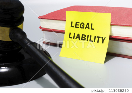 Judge's gavel with text legal liability on yellow note and red books. Judge's gavel with text legal liability on yellow note and red books. 115086250