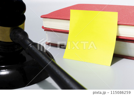 Judge's gavel with yellow note and red books on white background. 115086259
