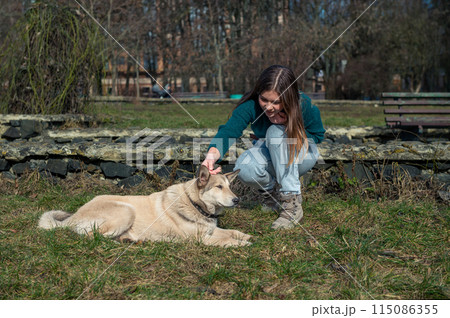 Beautiful teen girl with dog. Teenage girl playing with a dog in the park. 115086355