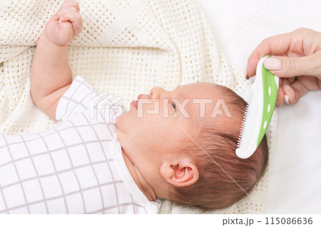 Mother combing her newborn babys hair Mother combing her newborn babys hair 115086636