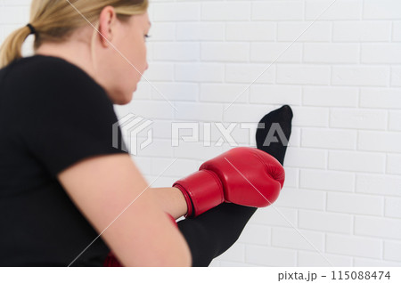 Female boxer stretching arms, warming up her body before intensive sport, wearing boxing gloves over white studio background. Sport. Cardo workout. People and active healthy lifestyle concept 115088474