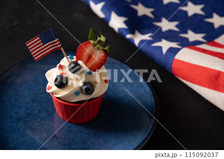American cupcake with sugar sprinkles as stars and USA flag in blue plate on black background. Dessert for Patriotic Independence Day 4th of July. Copy space American cupcake with sugar sprinkles as stars and USA flag in blue plate on black background. Dessert for Patriotic Independence Day 4th of July. Copy space 115092037
