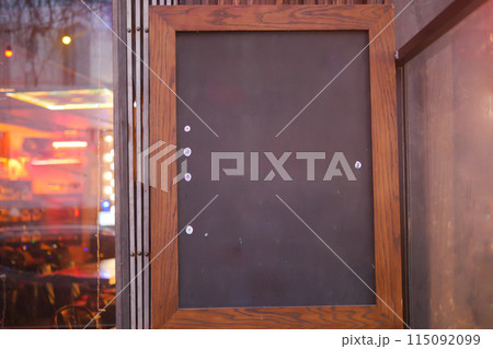 Empty wooden blackboard mockup standing outdoors in front of cafe  115092099