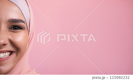 Joyful smile. Happy emotion. Half face portrait of amused satisfied pleased cheerful woman in hijab isolated on pink empty space background. 115092232