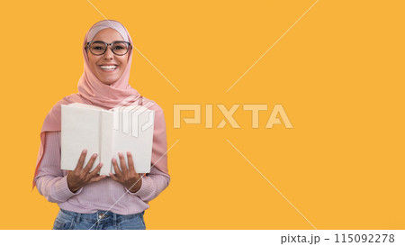 Reading hobby. Learning wisdom. Smart happy smiling woman in headscarf glasses with open book isolated on orange empty space background. Reading hobby. Learning wisdom. Smart happy smiling woman in headscarf glasses with open book isolated on orange empty space background. 115092278