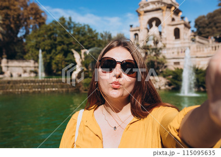 Young female tourist visiting Ciutadella Park in Barcelona. Young traveling woman taking selfie outdoors. Concept of travel, tourism and vacation in city. Use technology concept, Traveling Europe Young female tourist visiting Ciutadella Park in Barcelona. Young traveling woman taking selfie outdoors. Concept of travel, tourism and vacation in city. Use technology concept, Traveling Europe 115095635