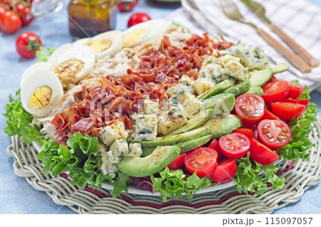 Cobb salad with greens, tomato, avocado, blue cheese, bacon, rotisserie chicken and eggs, horizontal 115097057