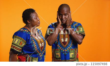 African american woman screaming at her boyfriend and starting argument in front of camera, yelling and causing fight. Young man feeling tired of conflict is covering his ears to ignore his wife. African american woman screaming at her boyfriend and starting argument in front of camera, yelling and causing fight. Young man feeling tired of conflict is covering his ears to ignore his wife. 115097498
