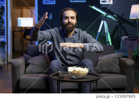 Smiling supporter watching sports match on live television broadcast, encouraging team. Joyous man looking at football competition, cheering for player to score winning goal 115097605
