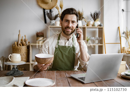 Happy male with new purchase in ceramics shop sitting at table. 115102730