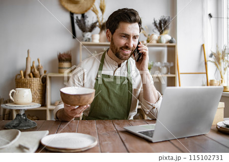 Happy male with new purchase in ceramics shop sitting at table. Happy male with new purchase in ceramics shop sitting at table. 115102731