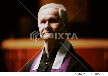 Closeup portrait of serious senior Caucasian Catholic priest looking at camera 115105186