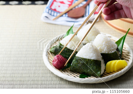 畳の上で食べる焼き海苔を巻いたおにぎりと昔ながらの酸っぱい梅干し 115105660