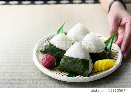 畳の上で食べる焼き海苔を巻いたおにぎりと昔ながらの酸っぱい梅干し 115105674