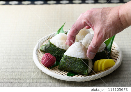 畳の上で食べる焼き海苔を巻いたおにぎりと昔ながらの酸っぱい梅干し 115105678