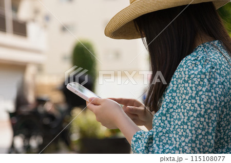 街角でスマホを操作する若い女性 115108077