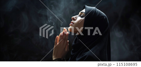A Muslim woman prays at night, her side profile illuminated by soft light. The background is dark, creating a peaceful night mood with ample copy space. Generative AI. 115108695