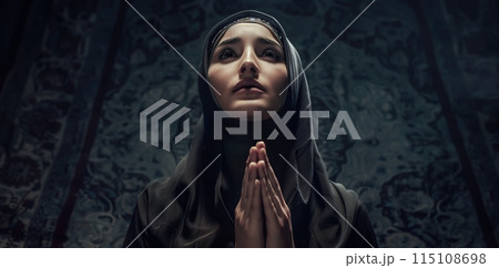 A Muslim woman prays at night, her side profile illuminated by soft light. The background is dark, creating a peaceful night mood with ample copy space. Generative AI. 115108698