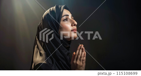 A Muslim woman prays at night, her side profile illuminated by soft light. The background is dark, creating a peaceful night mood with ample copy space. Generative AI. 115108699