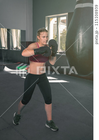 Women self defense girl power. Young female boxer is training with a punching bag in the gym Women self defense girl power. Young female boxer is training with a punching bag in the gym 115108939