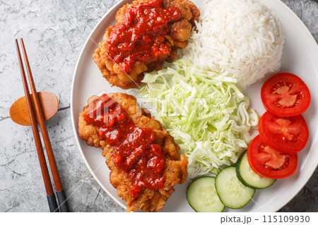 Ayam geprek Crispy Chicken Smashed in Sambal served with white rice, cucumber, tomato and cabbage closeup on the plate. Horizontal top view 115109930