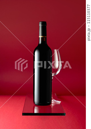 Bottle of red wine and an empty wine glass. Bottle of red wine and an empty wine glass. 115110377