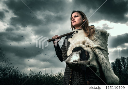 Portrait of woman in image of medieval warrior under dramatic sky. 115110509