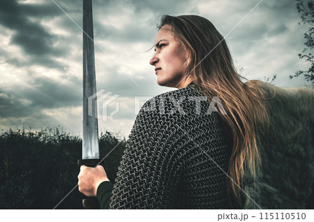Portrait of woman in image of medieval warrior under dramatic sky. 115110510