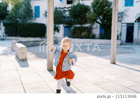 Little laughing girl runs through the tiled courtyard near the house Little laughing girl runs through the tiled courtyard near the house 115111606