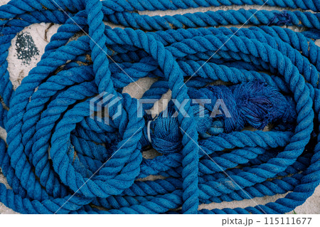 Blue rope with knots lies folded on the stone floor. Top view 115111677