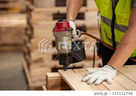Engineer carpenter wearing safety uniform and yellow hard hat working using electric nail gun Engineer carpenter wearing safety uniform and yellow hard hat working using electric nail gun 115112748