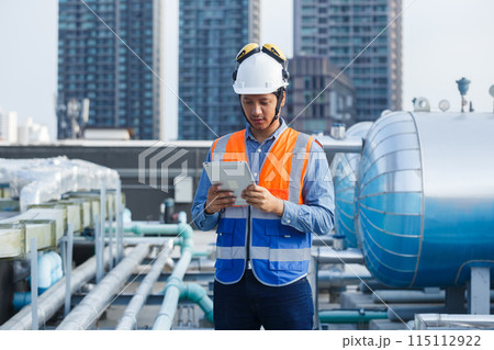 Asian man engineer holding tablet working at rooftop building construction. 115112922