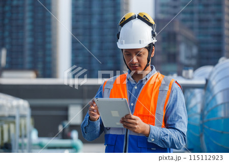 Asian man engineer holding tablet working at rooftop building construction. 115112923