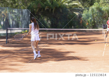 A woman is playing tennis on a clay court 115113614
