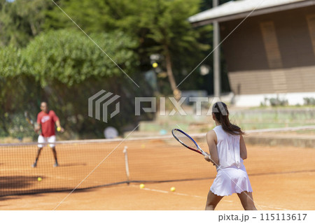 A woman is playing tennis with a man A woman is playing tennis with a man 115113617