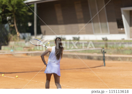 A woman is playing tennis on a clay court A woman is playing tennis on a clay court 115113618
