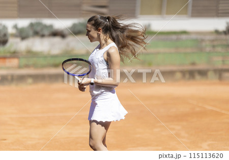 A woman in a white dress is holding a tennis racket A woman in a white dress is holding a tennis racket 115113620