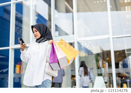 Muslim women wear hijab holding shopping bag color in supermarket. Muslim women wear hijab holding shopping bag color in supermarket. 115114276