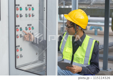 Electrical engineer man using tablet checks switchboard main Distribution Boards control panel 115114326