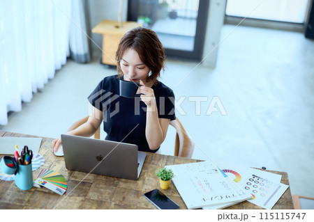 自宅でパソコンに向かって仕事をする女性デザ 115115747