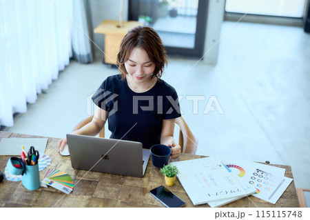 自宅でパソコンに向かって仕事をする女性デザ 115115748