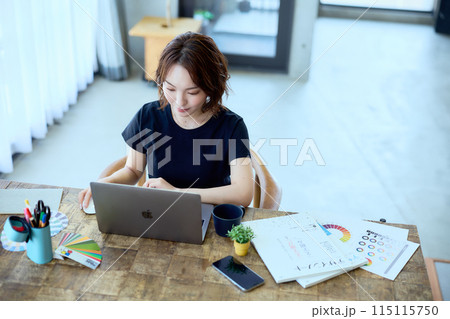 自宅でパソコンに向かって仕事をする女性デザ 115115750