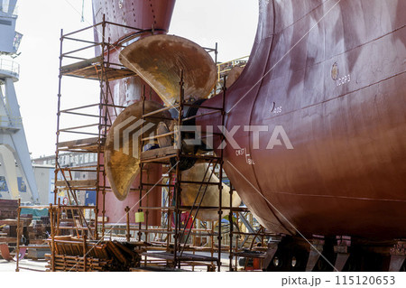 Cargo vessel in dry dock on ship repairing yard. Variable pitch propeller and rudder. 115120653